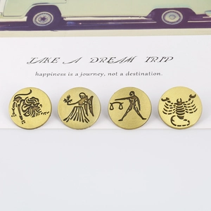 Close-up of four vintage bronze zodiac badges showing Leo, Virgo, Libra, and Scorpio