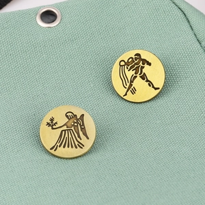 Detail of vintage bronze Aquarius and Virgo zodiac brooches on green fabric background
