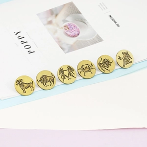 Detail of vintage bronze zodiac pins with brushed metal texture and retro emblems