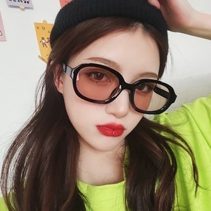 Close-up of model wearing black oval thick-frame sunglasses with vibrant red lenses