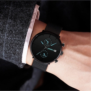 Macro detail of men's black mesh watch with blue hands and date window on wrist