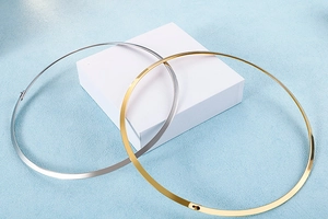 Polished titanium steel chokers in gold and silver set on white geometric blocks