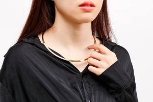 Polished gold choker necklace on collarbone paired with a black satin shirt outfit