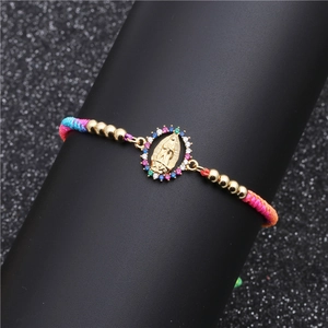 Detailed macro shot of Virgin Mary pendant with colorful zircons on braided bracelet
