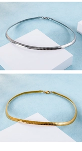 Dettaglio di collane a catena piatta oro e argento su basi bianche minimaliste ed eleganti