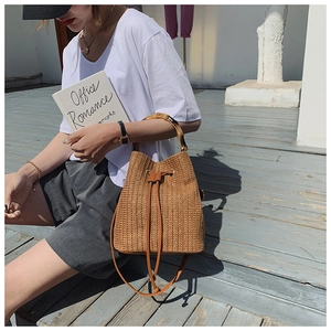 Close-up of vintage straw bucket bag with bamboo handle and brown leather drawstring