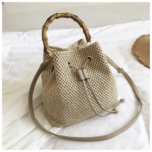 Detailed close-up of straw bucket bag with bamboo handle and drawstring closure