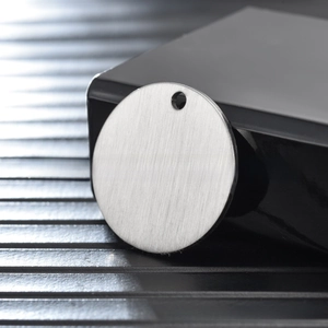Macro shot of brushed stainless steel round tag with pre-drilled hole for DIY jewelry