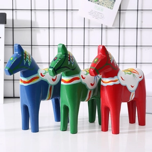 Three-piece set of wooden Dala horses in red, blue, and green with hand-painted patterns