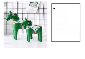 Detail of green Dala horses with hand-painted floral motifs on minimalist wooden stands