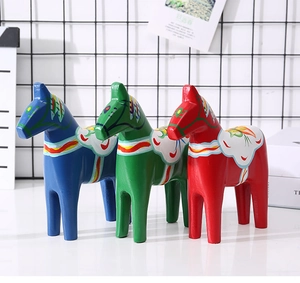Detailed view of three hand-painted wooden Dala horses in blue, green and red colors