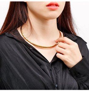 Close-up of minimalist gold titanium cross choker necklace worn by a fashion model