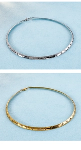 Close-up of gold and silver choker necklaces featuring engraved cross patterns