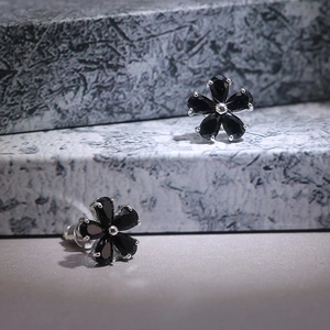 Close-up of five-petal flower earrings with black zircon stones and silver plating
