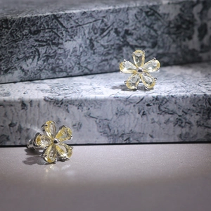 Detailed view of yellow zircon flower studs with pear-cut petals on marble pedestals