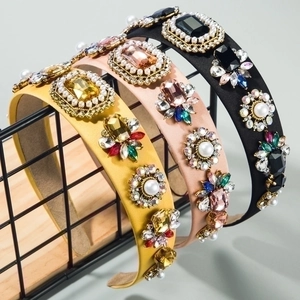 Detail of baroque headbands with sewn crystals and pearls on satin fabric texture