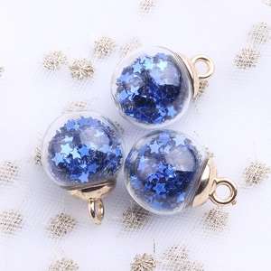 Macro shot of glass ball pendants with blue star sequins and gold hanging loops