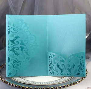 Detail of laser cut cyan invitation card with intricate lace pattern on white plate
