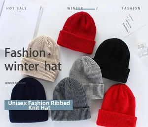 Flat lay of colorful thick knitted beanies in red, black, and beige with a stylish setup