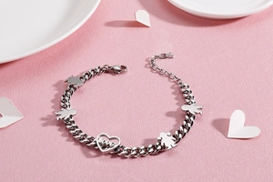 Silver Cuban link bracelet with heart love charm and family figures on pink background