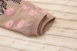 Close-up of ribbed cuffs and pink donut pattern on cotton knitted brown crew socks