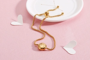 Detail of gold Sagittarius zodiac bracelet with engraved coin charm on white porcelain plate