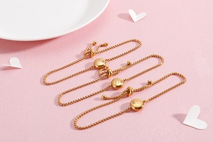 Close-up of gold zodiac charm bracelets with Gemini engraving and adjustable chain
