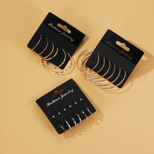 Dreiteiliges geometrisches Set aus goldenen und silbernen Creolen auf schwarzer Karte