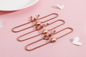 Detail of rose gold zodiac bracelets with Aries Taurus Gemini charms on soft pink background