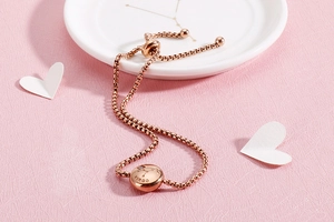 Detailed view of rose gold Virgo constellation bracelet with cubic zirconia on pink texture