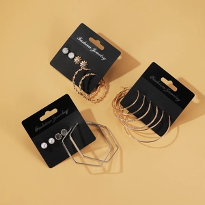 Set mit geometrischen Creolen in Gold und Silber sowie Perlen auf gelbem Hintergrund
