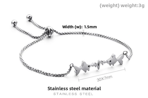 Macro shot of stainless steel fish charm bracelet with adjustable sliding bead and box chain