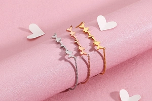 Three-color heartbeat fishbone bracelets in gold, rose gold and silver on pink background