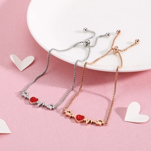 Silver and rose gold heartbeat bracelets with red diamonds on a white ceramic plate