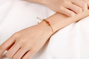 Detail of gold heartbeat heart bracelet with red crystals on a model wrist