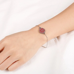 Silver chain bracelet with red circular flower pendant on wrist for women's style
