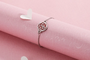 Détail macro du bracelet rose évidé en argent avec émail rouge sur papier rose texturé