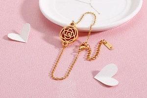 Détail du pendentif rose dorée évidée avec émail rouge sur une chaîne à maillons fine