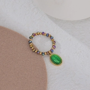 Elastic beaded ring featuring gold and green beads with a Virgin Mary religious pendant