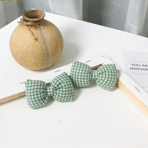 Détail de pinces à cheveux à nœuds à carreaux vert et blanc en coton sur un bureau