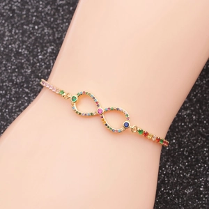 Macro view of gold infinity bracelet with multi-color zircon stones on black background