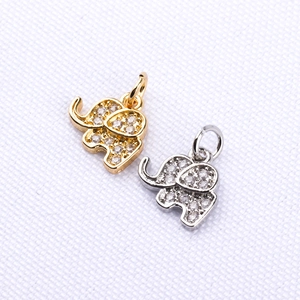 Micro shot of gold and silver elephant pendants with zircons on white fabric