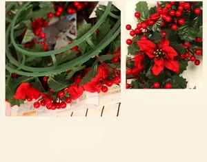 Detail shot of artificial red poinsettia and berries on a green plastic wreath base