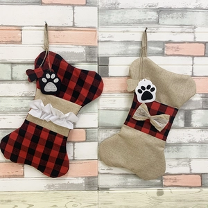 Detail of bone-shaped plaid Christmas stockings with cute paw tags on a brick background