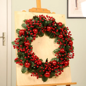 Christmas wreath with red berries and green leaves displayed on a wooden easel stand