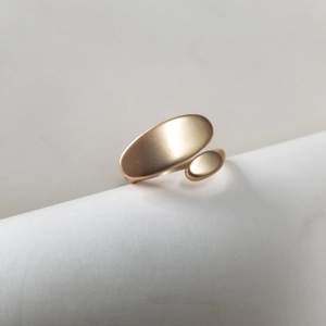 Macro detail of golden oval pea ring featuring matte finish and minimalist organic curves