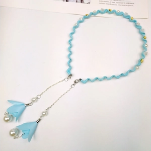 Detail of light blue ribbon choker with pearls and long tassel pendant chains