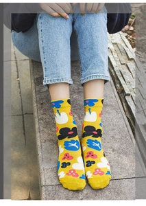 Detail of yellow cotton socks with blue floral patterns worn by a model in outdoor lighting