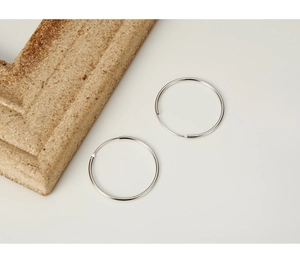 Close-up of minimalist S925 sterling silver hoop earrings on a vintage stone background