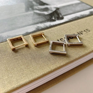 Detailed view of square S925 sterling silver hoop earrings in gold and silver finishes